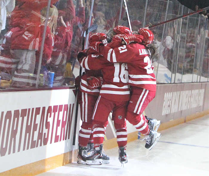 Wisconsin's Nicole LaMantia (21) and Claire Enright (16) are among the players who are part of a group hug after Kirsten Simms scored during the first period of the NCAA Division I women's hockey final Sunday March 19, 2023 at AMSOI: Arena in Duluth, Minn. Uwice Ohio State 8 March 19 2023